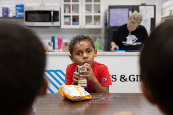 AJ wears a red shirt and drinks a juice box at the Boys and Girls Club in Waynesboro.