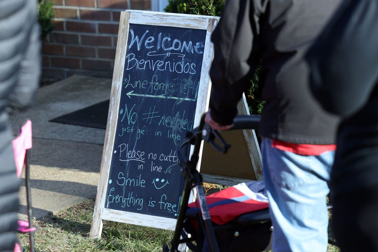 Photo of a sign in front of River City Bread Basket where someone has written "Welcome. No # needed just get in line. Please no cutting in line. Smile, everything it free!"