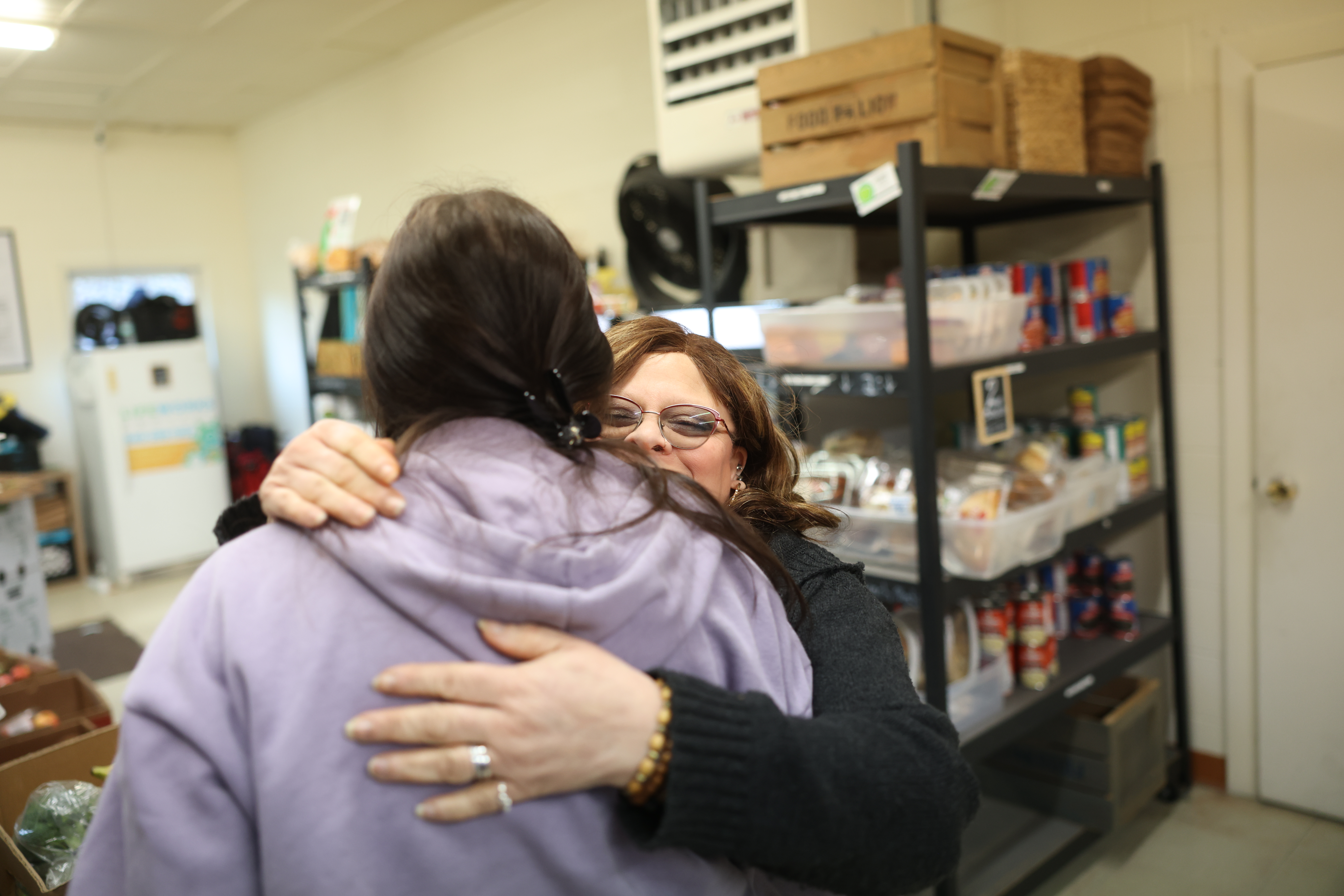As she does with many of her guests, pantry director Adrienne Young at River City Bread Basket food pantry in Waynesboro (with glasses), gives one of her guests a big hug. 