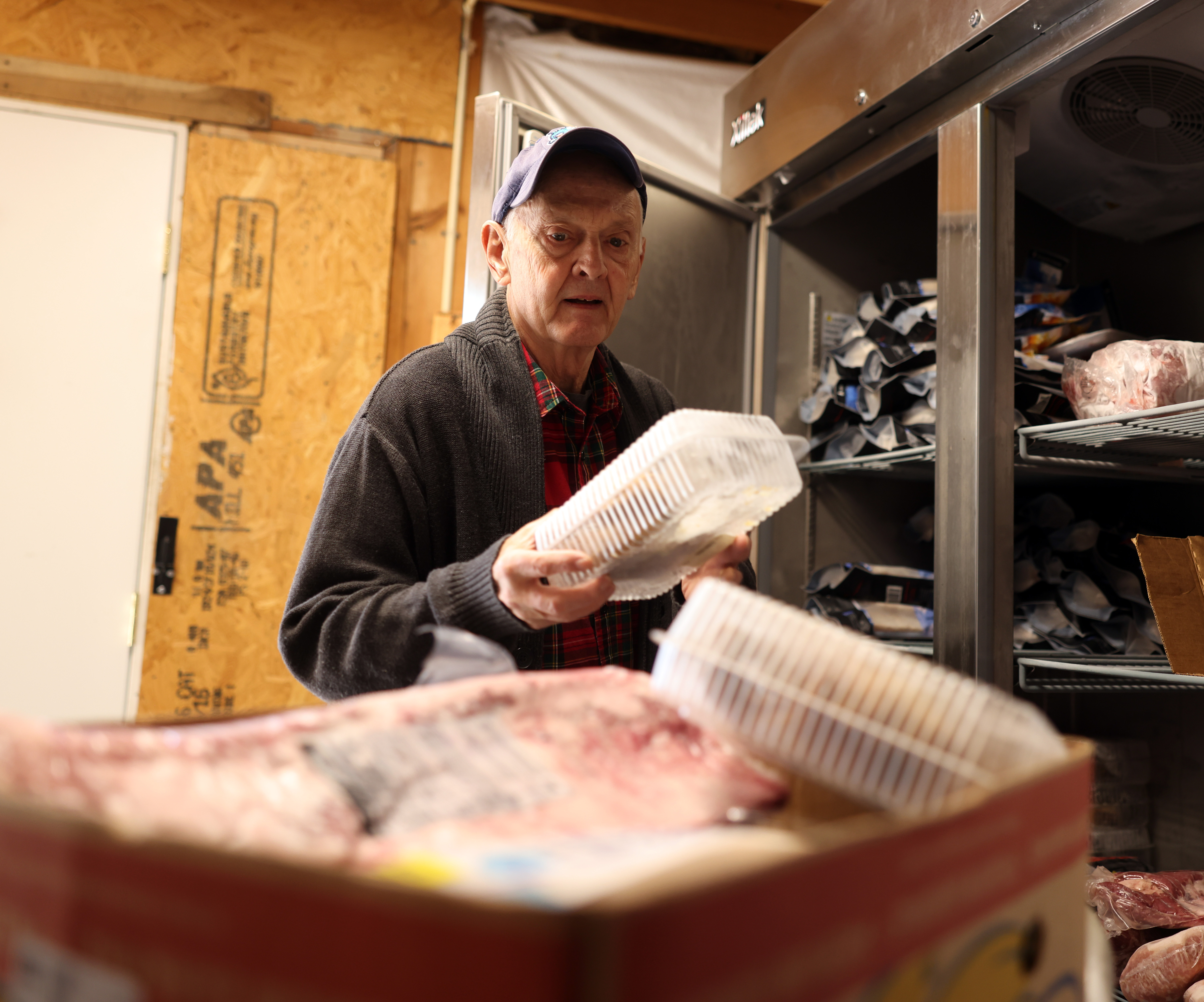 A volunteer puts food in a box for a guest who's waiting for the food in their car.